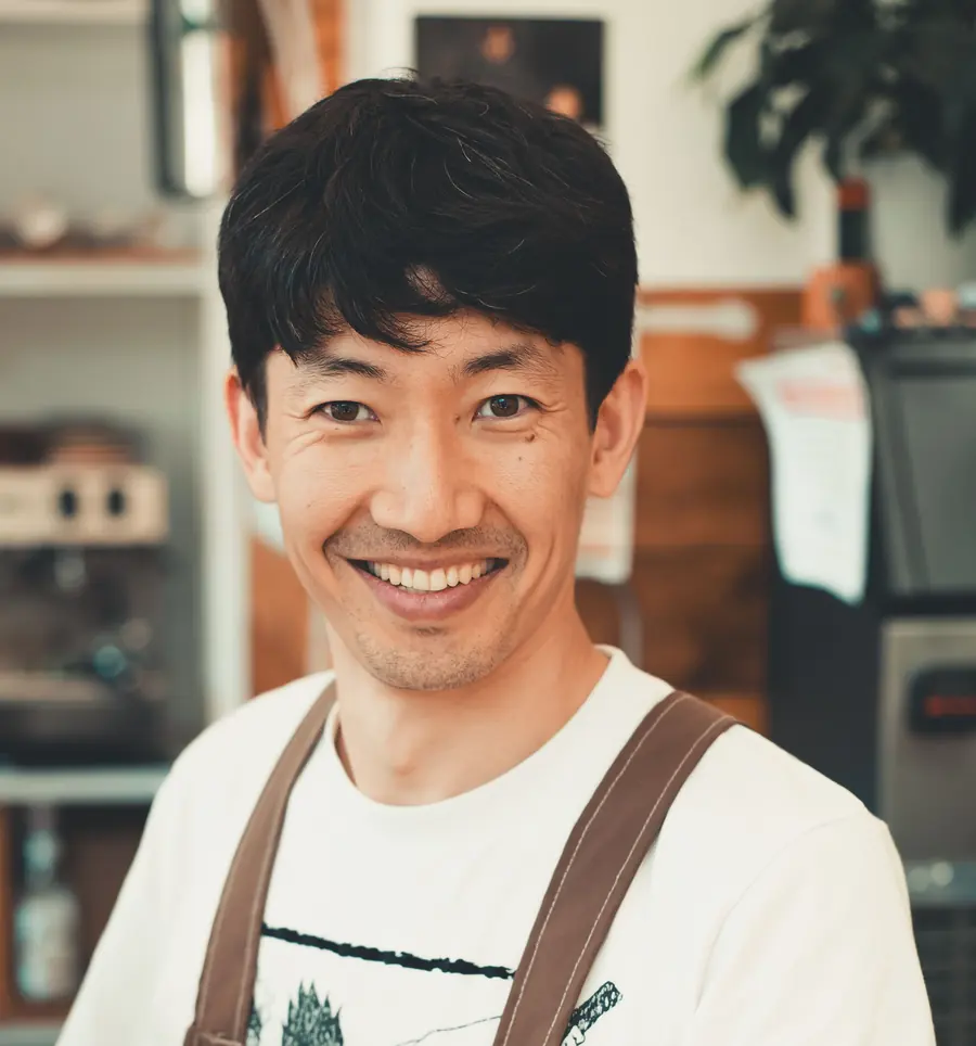 A barista smiling behind a cafe counter